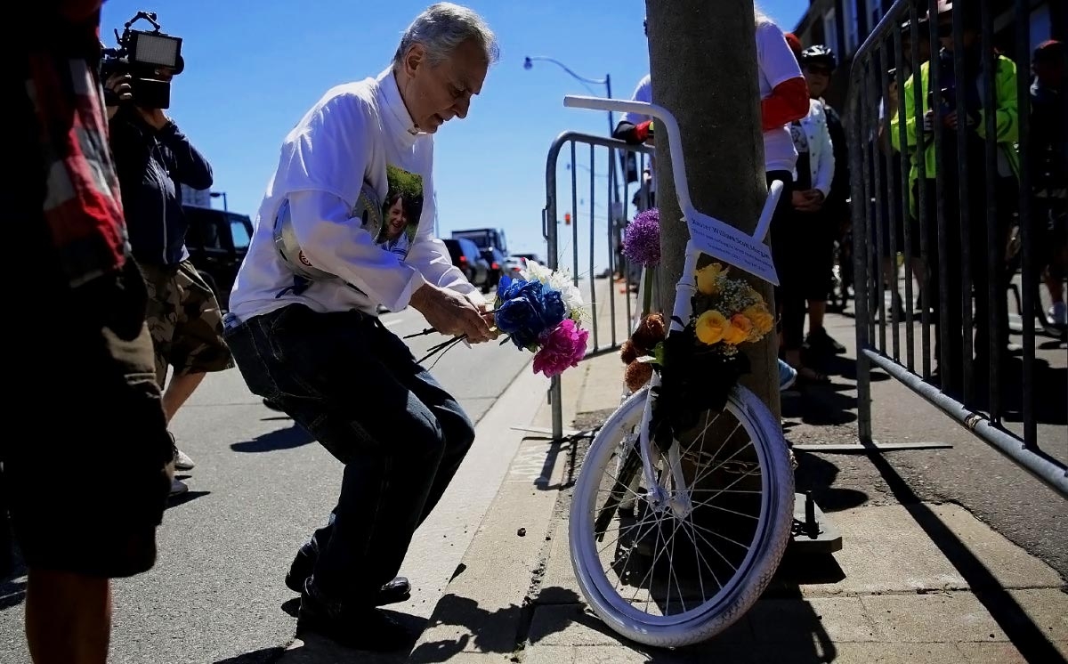 Скотт Морган, дедушка Ксавье Моргана, сбитого машиной на бульваре Lake Shore в Торонто, кладёт цветы к мемориальному белому, байку (ghost bike), на месте аварии.